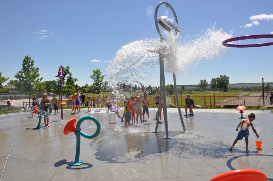 Children standing under bucket dumping water at the outdoor water spray park