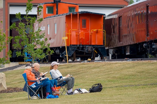 people sit in lawn chairs in front of a train car