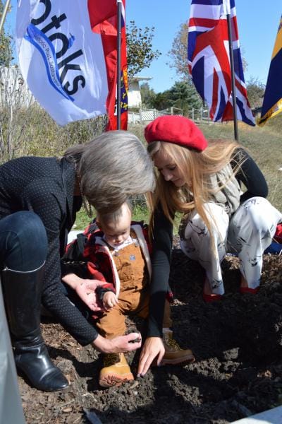 Photo of Mom, Daughter, and Baby planting tulips.