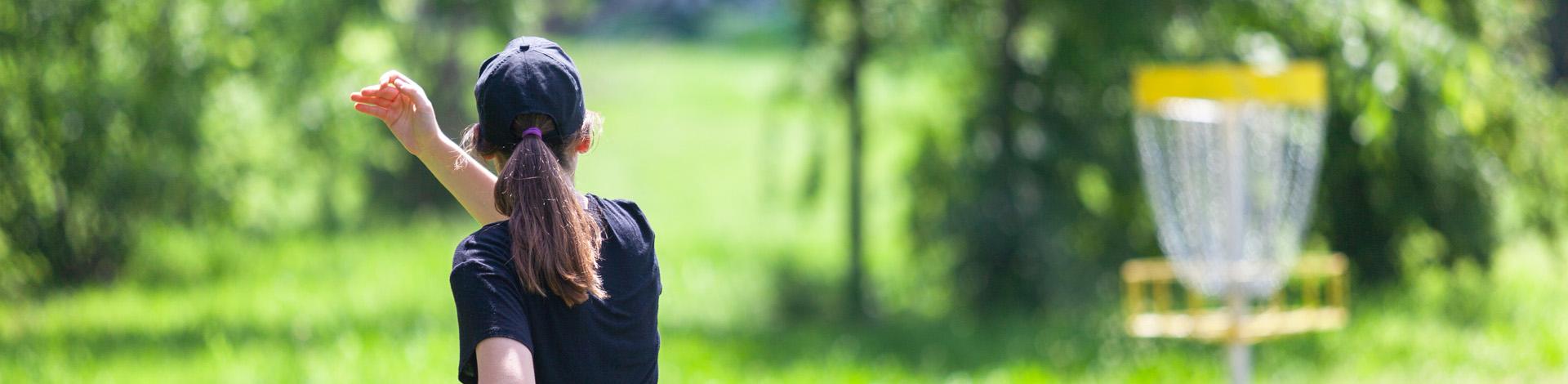woman playing disc golf in park