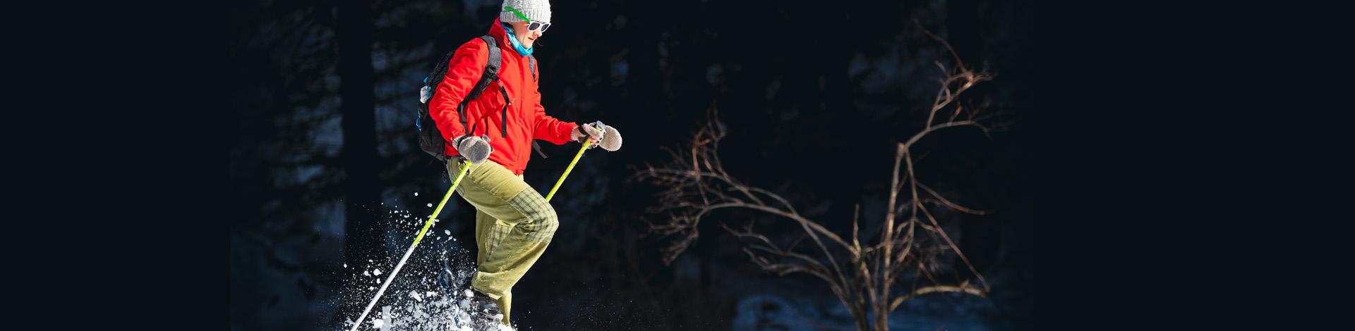 woman snowshoeing in red coat on dark background