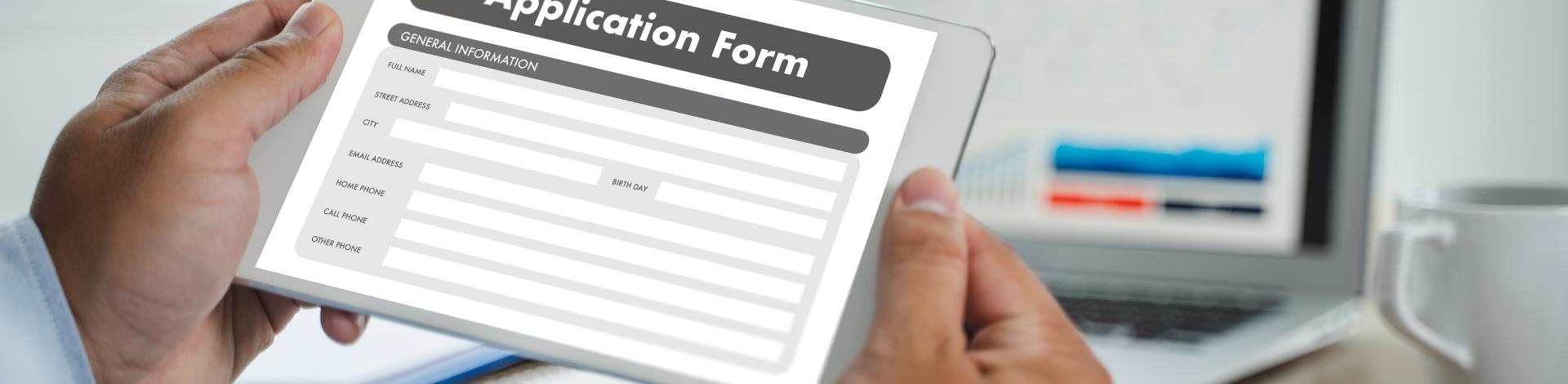Person holding a tablet submitting an online application form