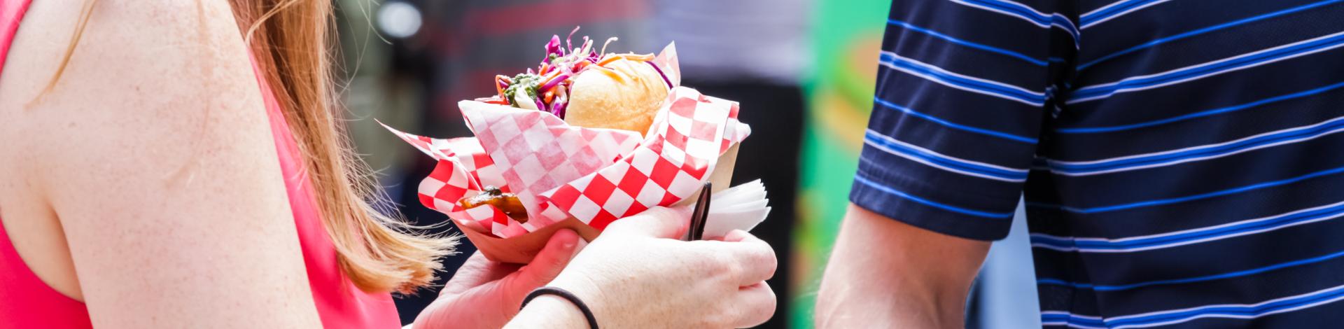 person eating food from vendor booth at street food festival: Taste of Okotoks