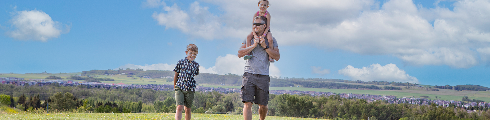 Dad enjoying outdoors with son and daughter on his shoulders