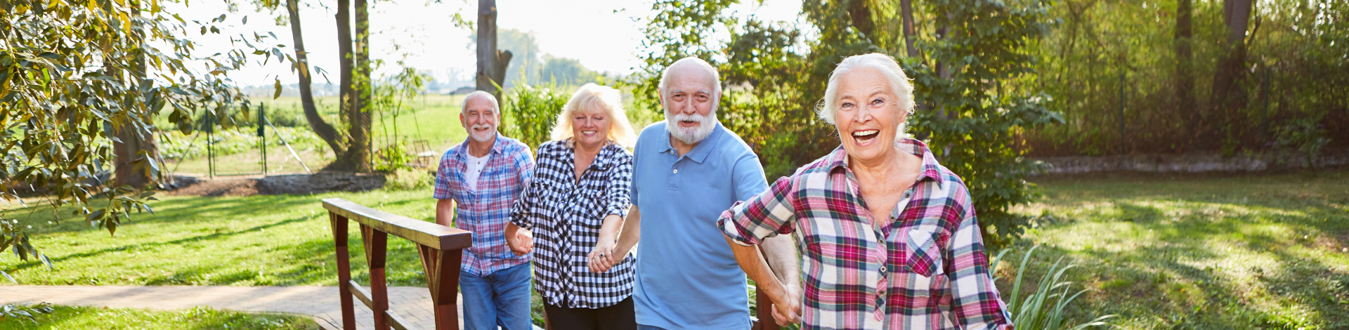 two senior women and two senior men holding hands on a bridge outdoors