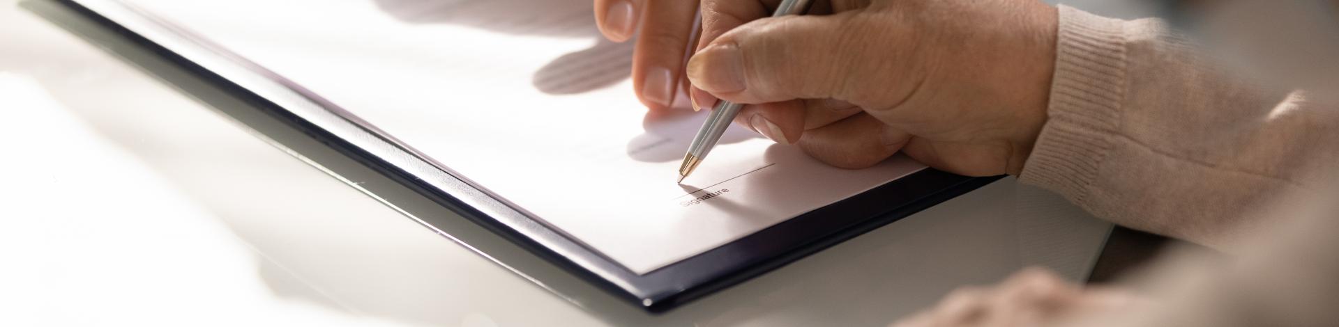 Hands of one person showing another person where to sign on a registration form