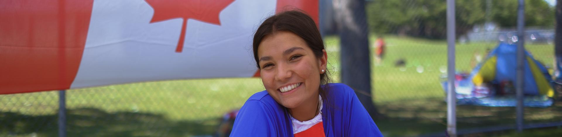 Teenager smiling and sitting in front of Canada flag
