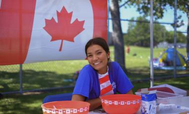Teenager smiling and sitting in front of Canada flag