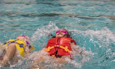 child swimming in pool with life jacket