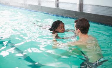 little girl learning to swim with instructor