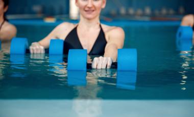 female in group aqua aerobics class with dumbbells in pool