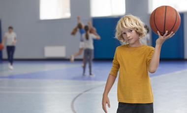 young boy holding basketball in gymnasium