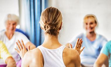 instructor teaching yoga to smiling seniors