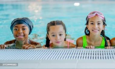 Three female children smiling in swimming pool
