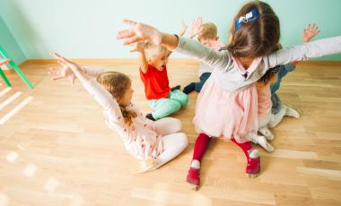 happy kids playing on wooden floor holding hands up