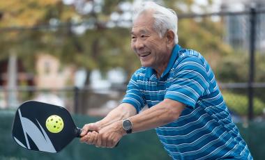 senior man smiling playing pickleball