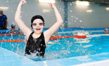 young girl raising arms in air in pool