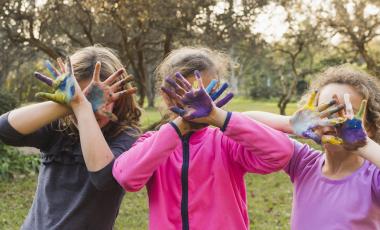 three girls covering their faces with painted palms