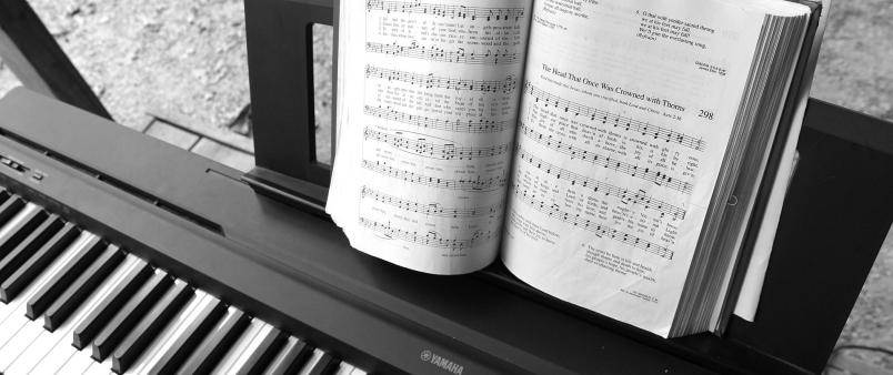 Electric piano keyboard with open music book on top.