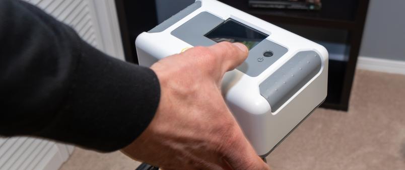 hand holding Radon monitor in bedroom of a home