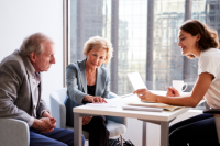 senior couple receiving advice from business woman in office building