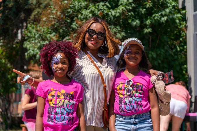 Children in pink shirts with faces painted standing with their mom