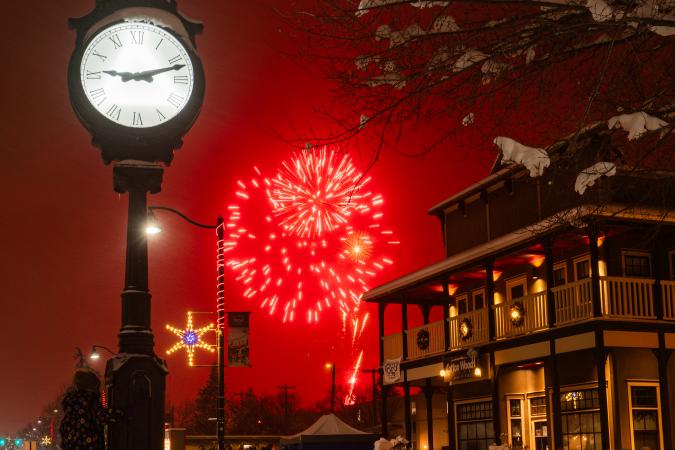 downtown plaza clock with red fireworks in background during Light up festival