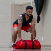 Individual carries red weighted bag during PARE training