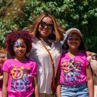 Children in pink shirts with faces painted standing with their mom