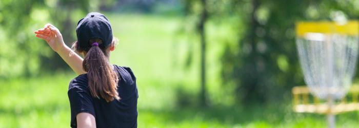 woman playing disc golf in park