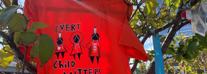 Orange shirt hanging in the tree with text that says "Every Child Matters."