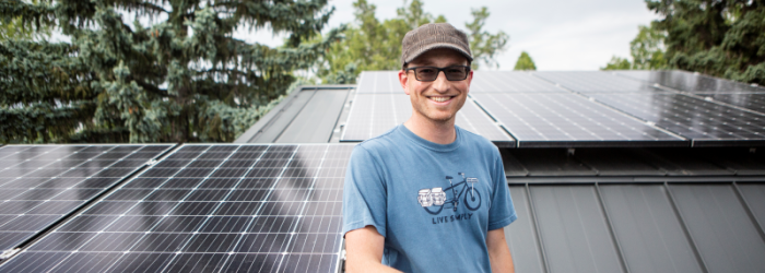 man standing on roof beside solar panel installation 