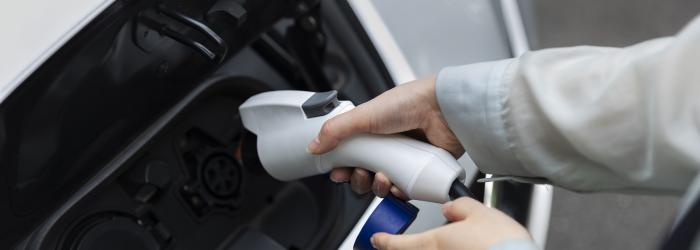 Woman holding charge port to charge her electric vehicle 