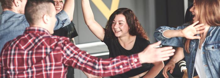 6 youth play foosball and high five while smiling 