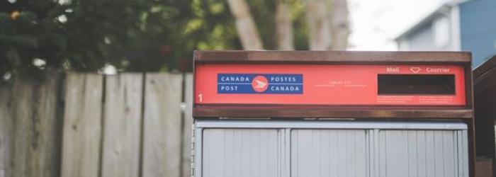 Canada Post community mailbox in front of fence