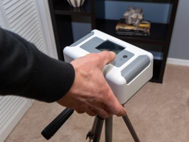 hand holding Radon monitor in bedroom of a home